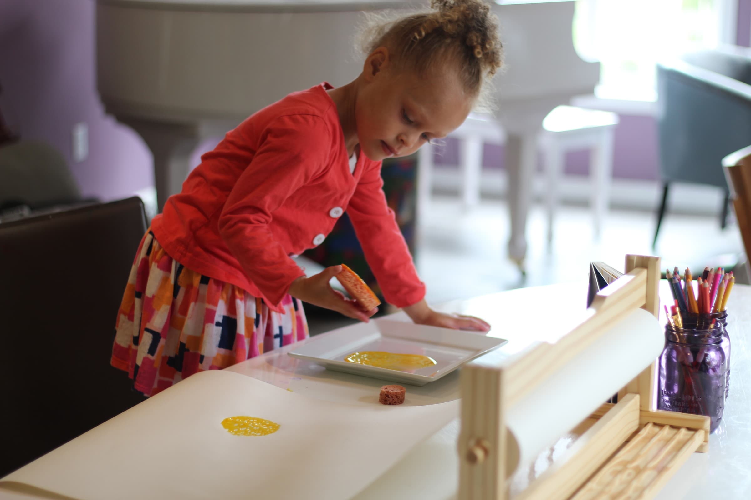 Girl painting colorful dots with sponges and paint during Digital Drawing class